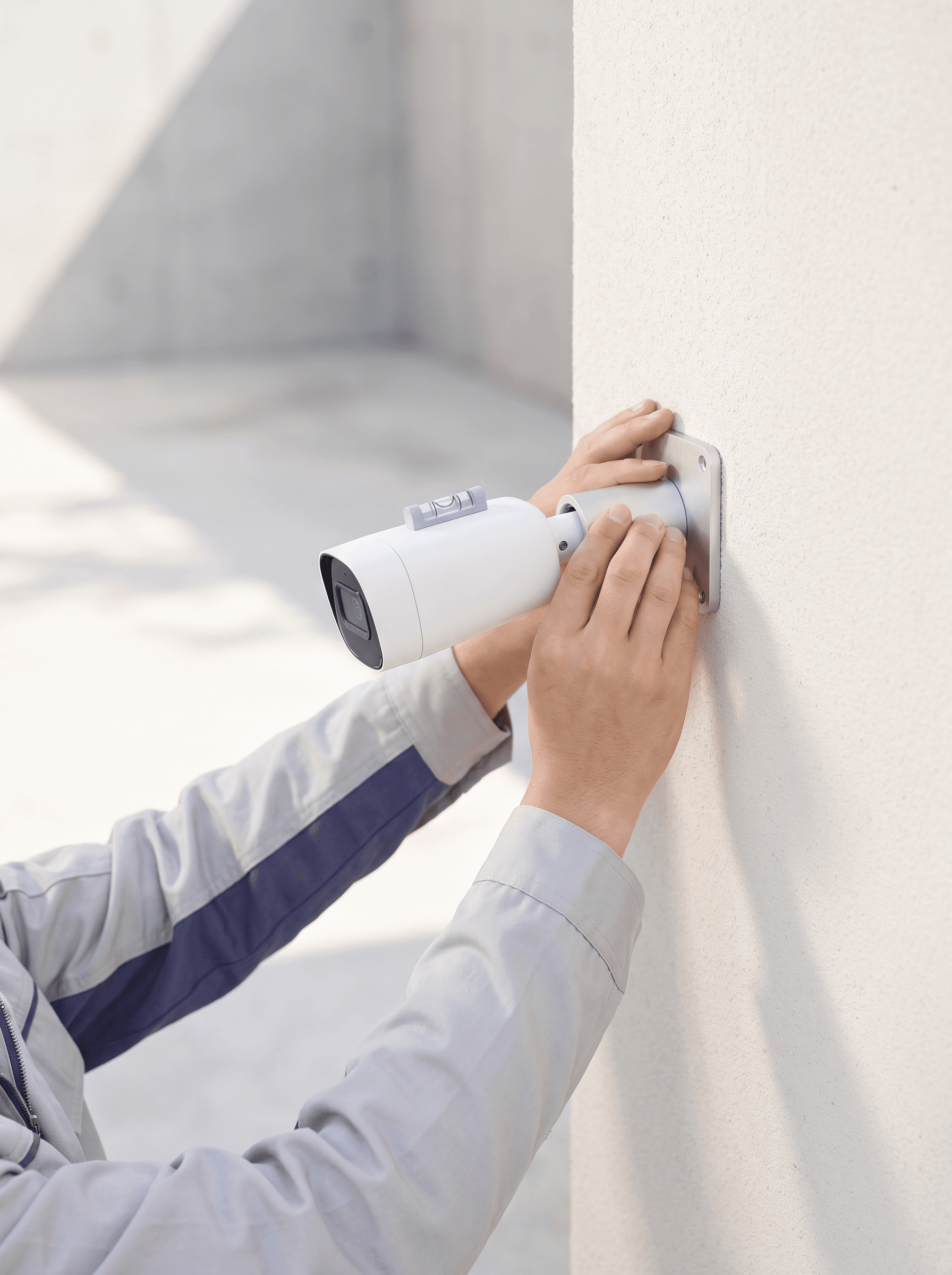 Technician fitting a bullet camera to a rendered wall