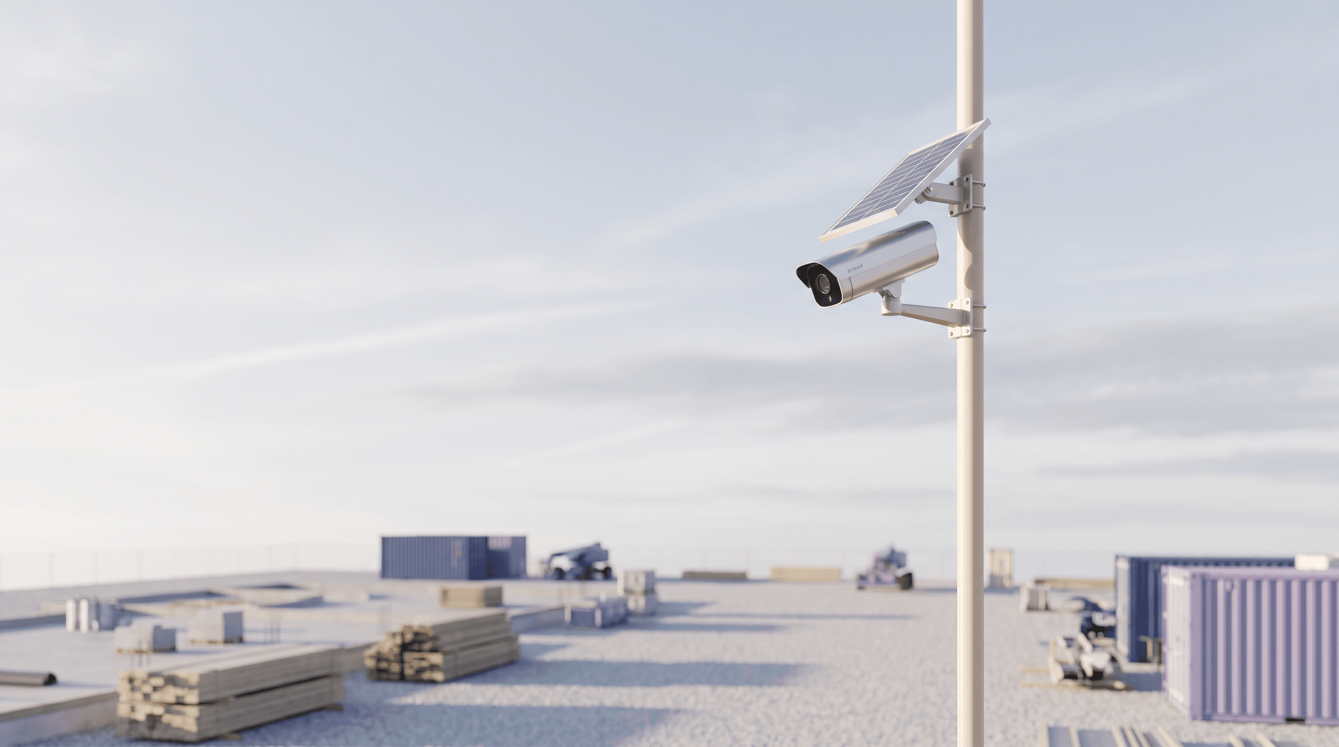 Solar camera on a slim pole overlooking an open site under a pale sky